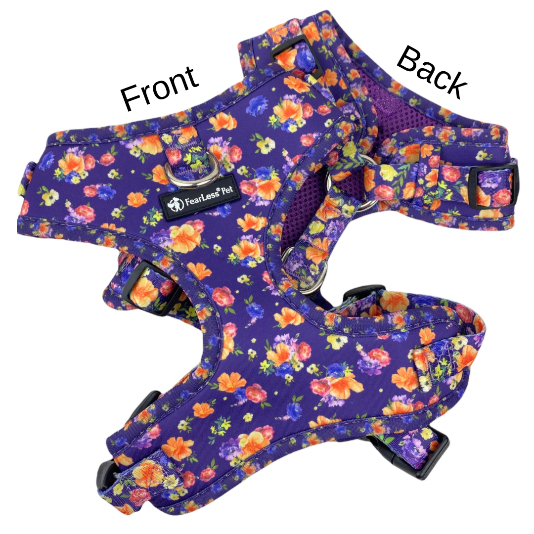 a photo of the front and back of a purple floral harness on a white background the harness has a front clip and is a no escape harness with neck adjusters